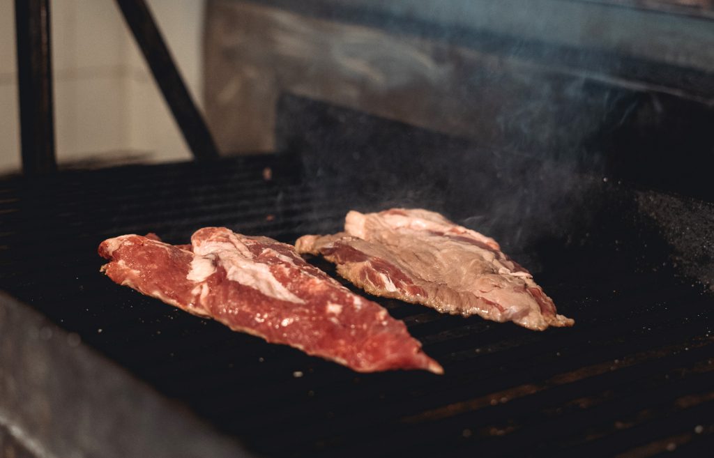 Vista de 2 filetes de secreto ibérico horneándose en la parrilla.